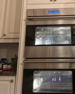 Wolf double wall oven after the repair, display on and both oven lights lit.